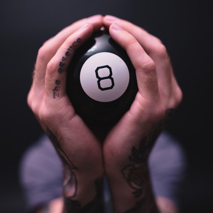 Zwei Hände halten eine schwarze Billard-Kugel mit der Nummer acht darauf.