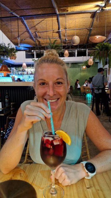 Frau mit blonden Haaren trinkt ein Getränk mit Obstscheiben in einem Restaurant.