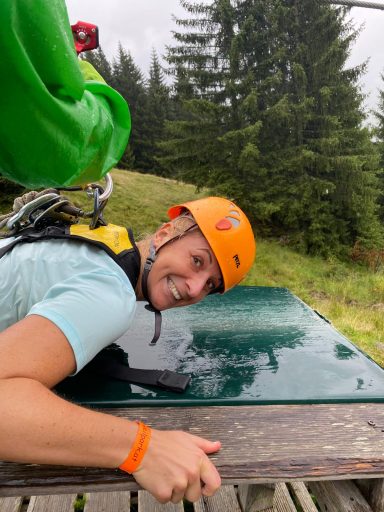 Ein Mann mit Helm liegt auf einem Tisch in der Natur, lächelt und blickt zur Kamera.